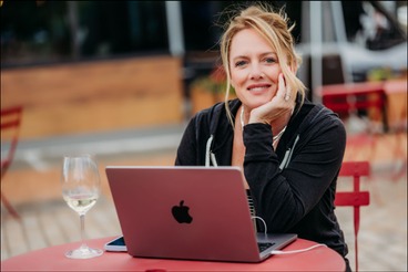Jennifer Antoine working at an outdoor cafe table with her laptop
